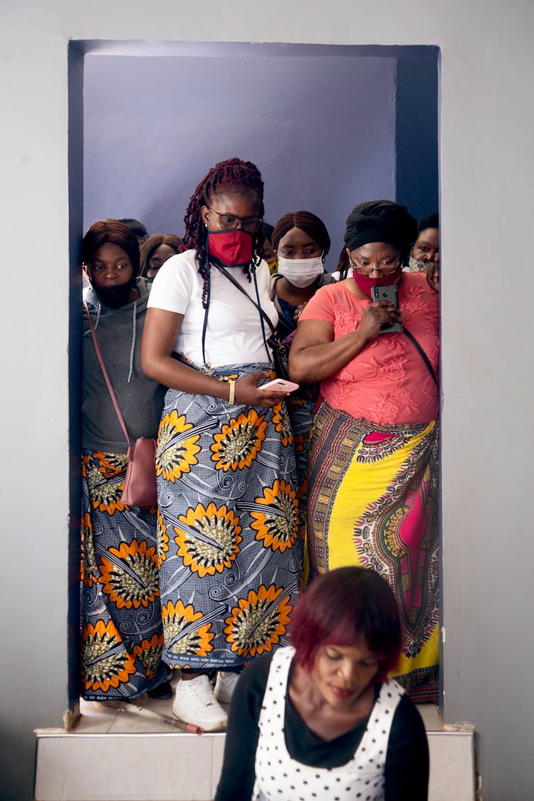 Women In Face Masks And Skirts In A Doorway