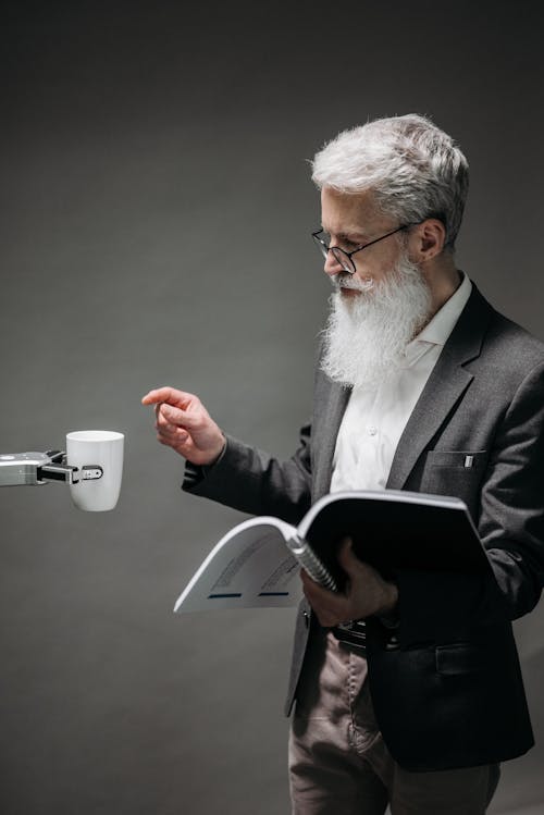 Robot Handing a Mug of Coffee to a Man Reading Technical Documentation