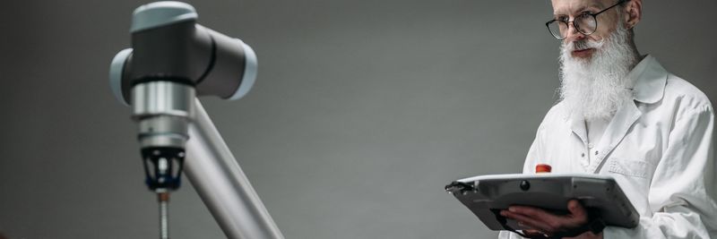 Senior scientist observing robot performing a task indoors.
