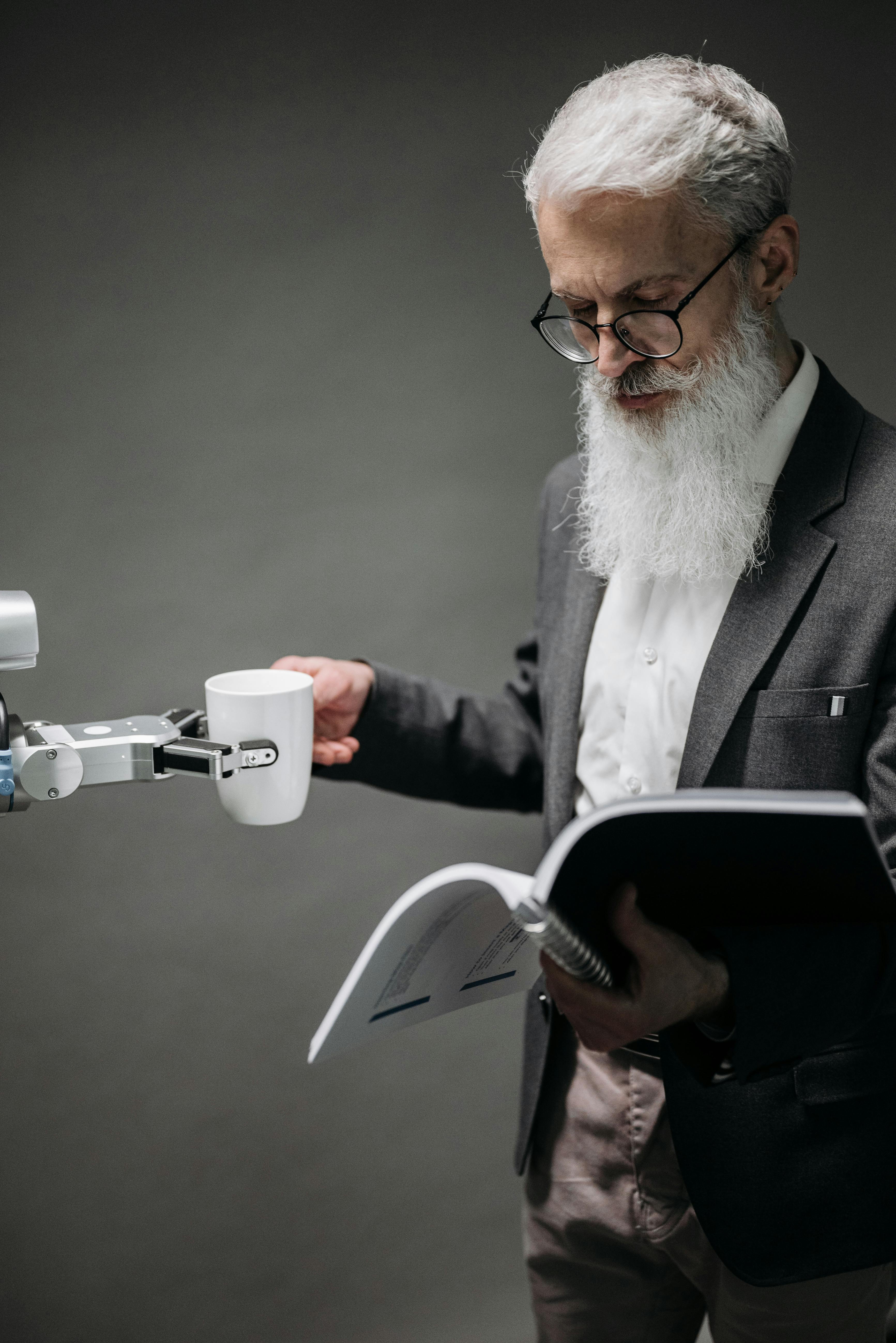 reading man taking coffee from a robot