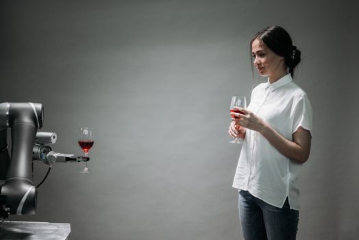 A robot presents a glass of wine to a woman, showcasing modern technology and interaction.