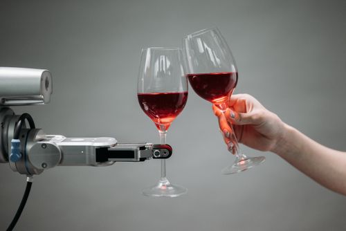 Free A robot and a human hand clinking glasses of red wine, symbolizing technology and celebration. Stock Photo
