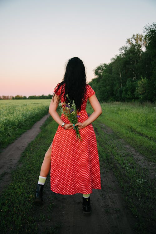 Free Woman in Red and White Polka Dot Dress Standing on Green Grass Field Stock Photo