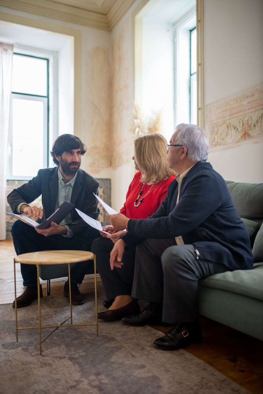 An advisor discussing a family's legacy plan with a senior couple in a warm, comfortable setting