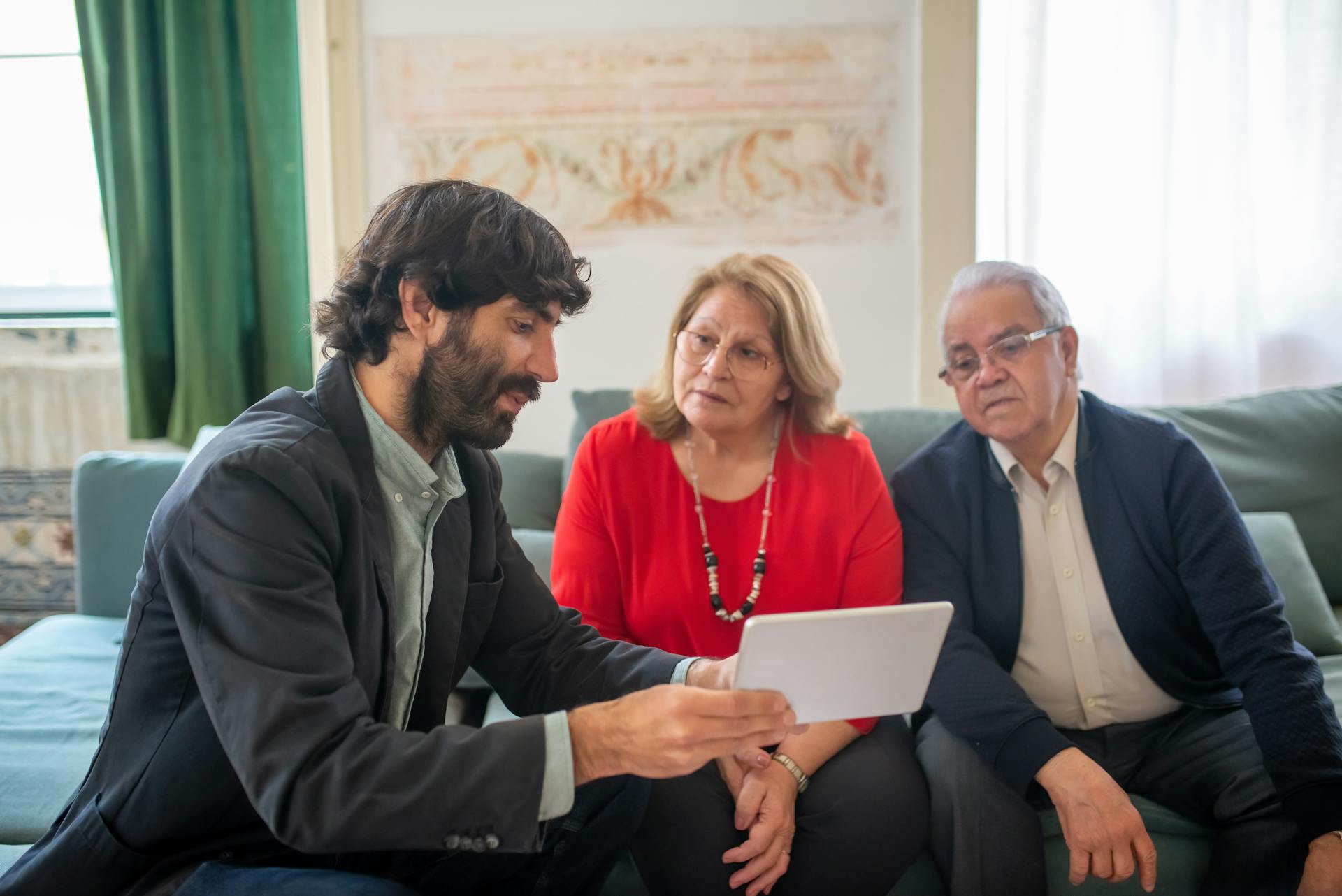 Broker Presenting an Offer to an Elderly Couple on a Tablet