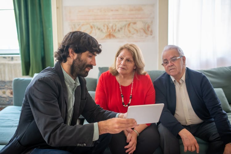 Broker Presenting An Offer To An Elderly Couple On A Tablet 