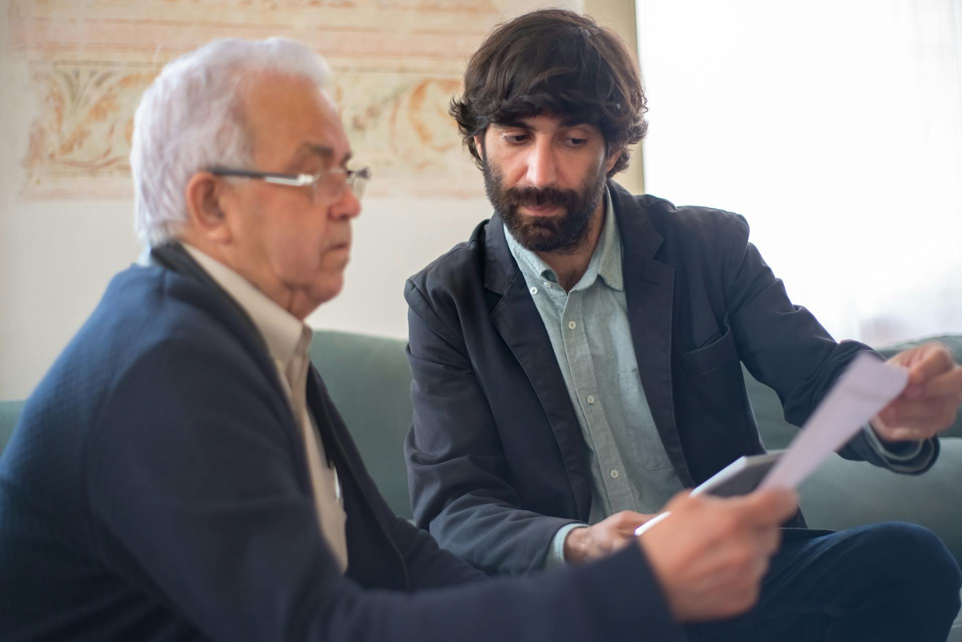 Bearded Man Showing an Elderly Client a Document