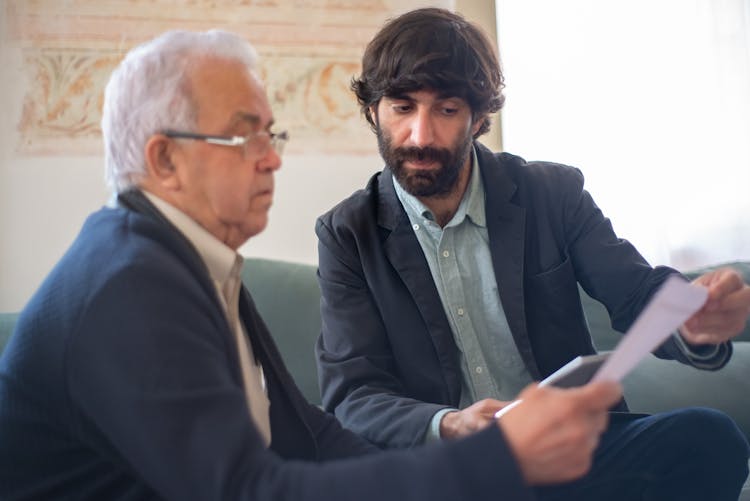 Bearded Man Showing An Elderly Client A Document