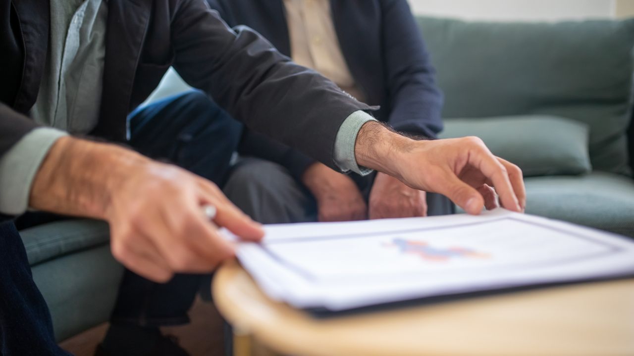 Two men discussing documents during a business meeting, focusing on paperwork.