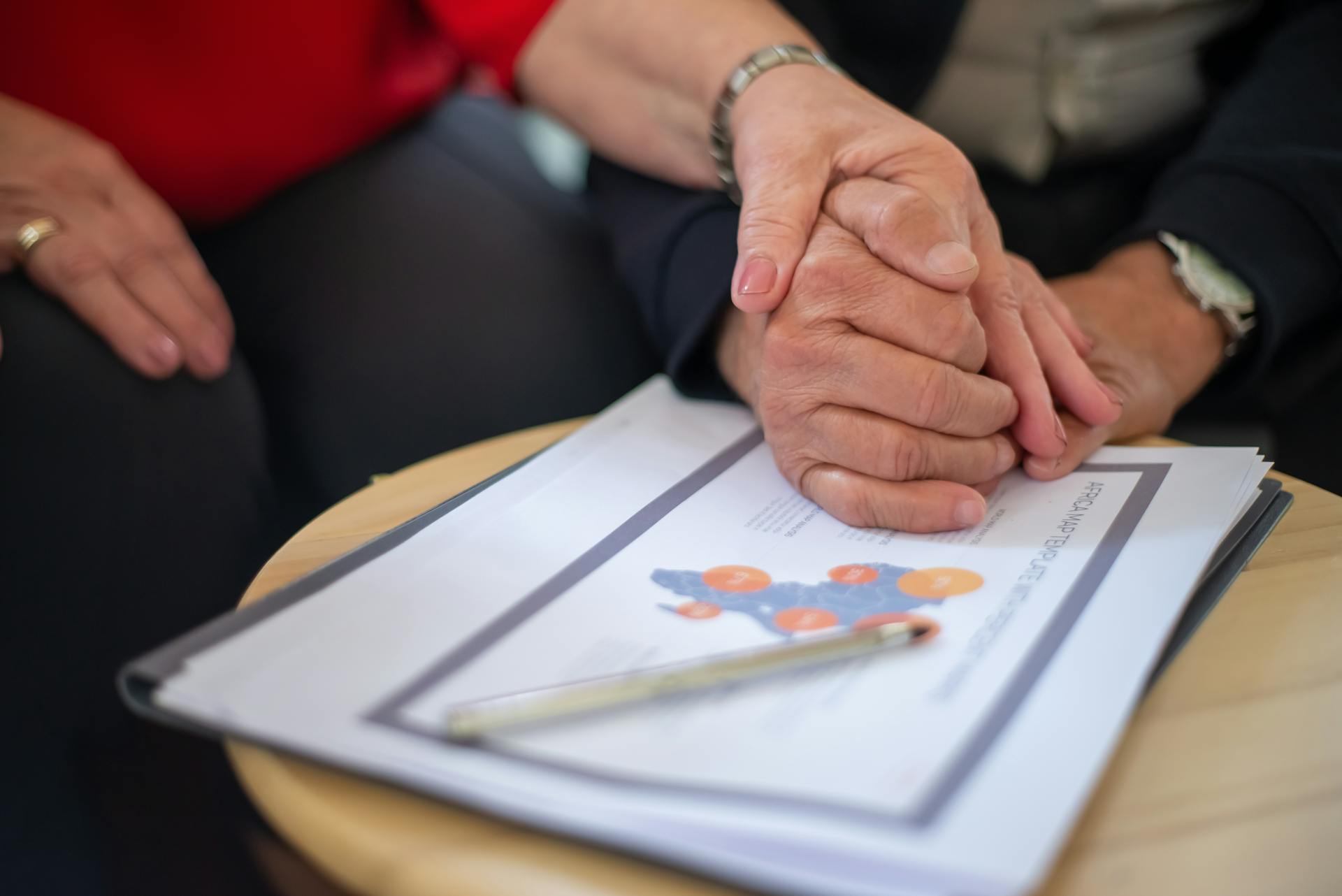 A Couple Holding Hands on Top of Documents