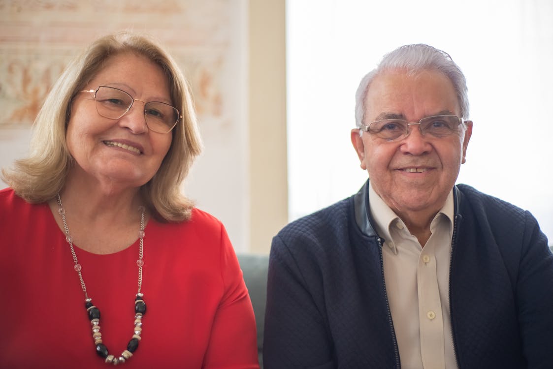 Free Elderly couple smiling and sitting together indoors, showcasing happiness and companionship. Stock Photo