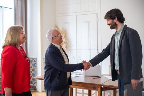 Free Elderly couple sealing a business deal with a handshake in a bright office. Stock Photo