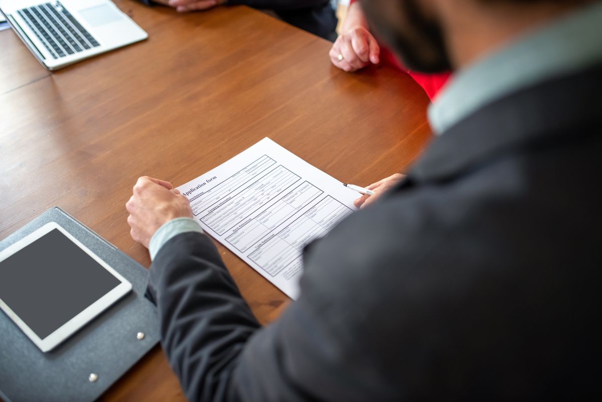 Man reading an application form at an office desk, reviewing a request before approving it