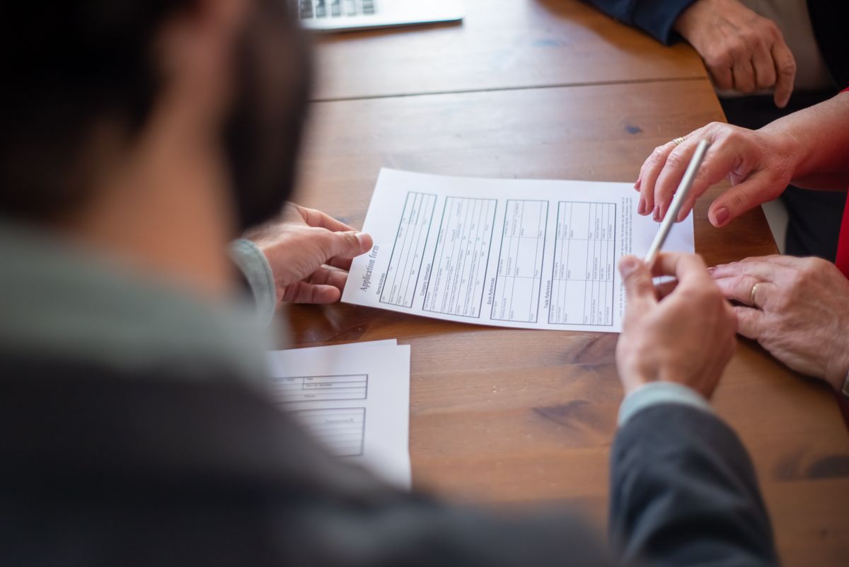 Insurance agent handing a pen to a client during a claims consultation