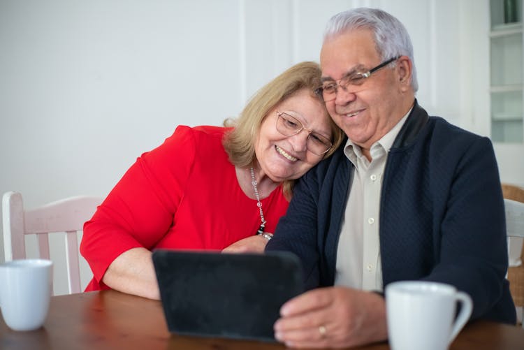 Woman Leaning On Man's Shoulder While Watching On Tablet 