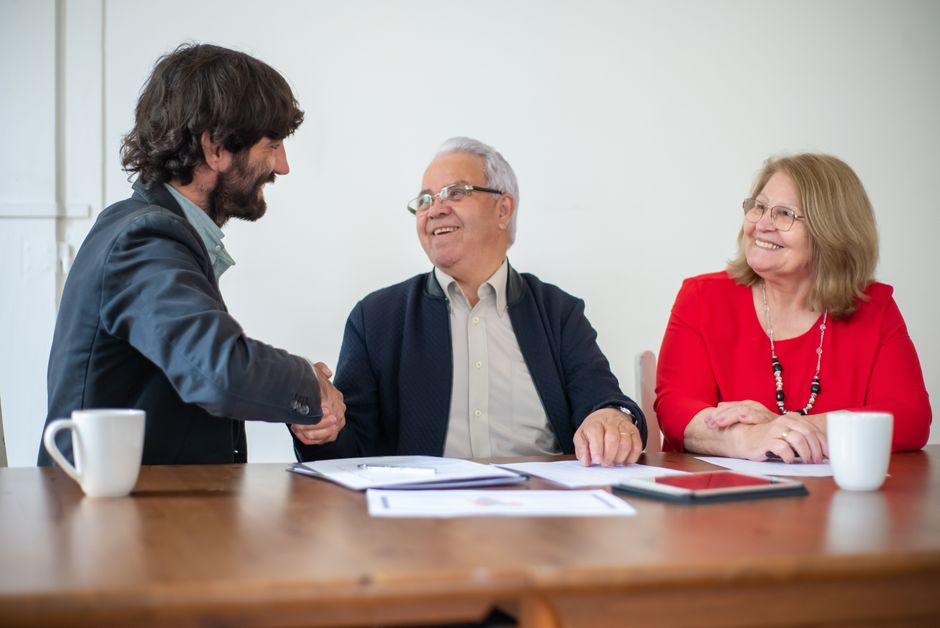 Couple shaking hands with a wedding vendor at a consultation table