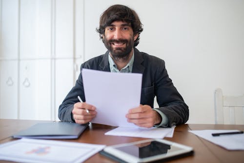Bearded Man in Black Jacket Holding Papers
