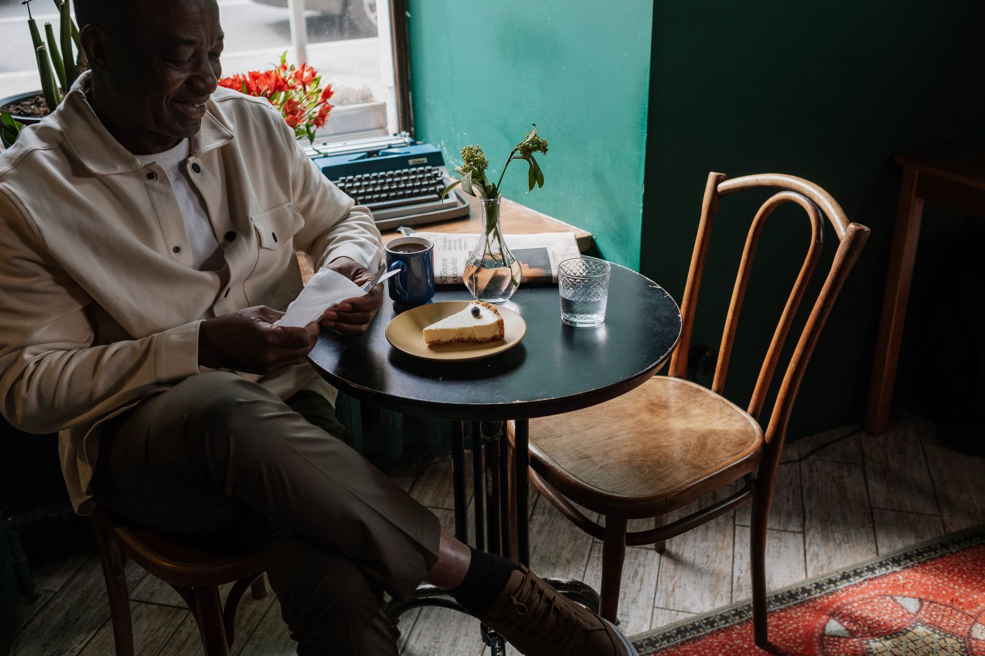 Smiling Man in White Shirt Sitting at the Table with Cheesecake and Cup of Coffee on It