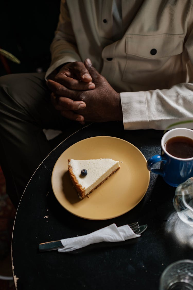 Cheesecake On Yellow Plate Beside Coffee Cup On Black Table