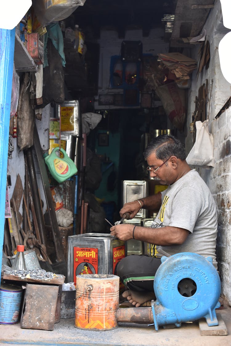 A Shopkeeper Working On A Tin Can