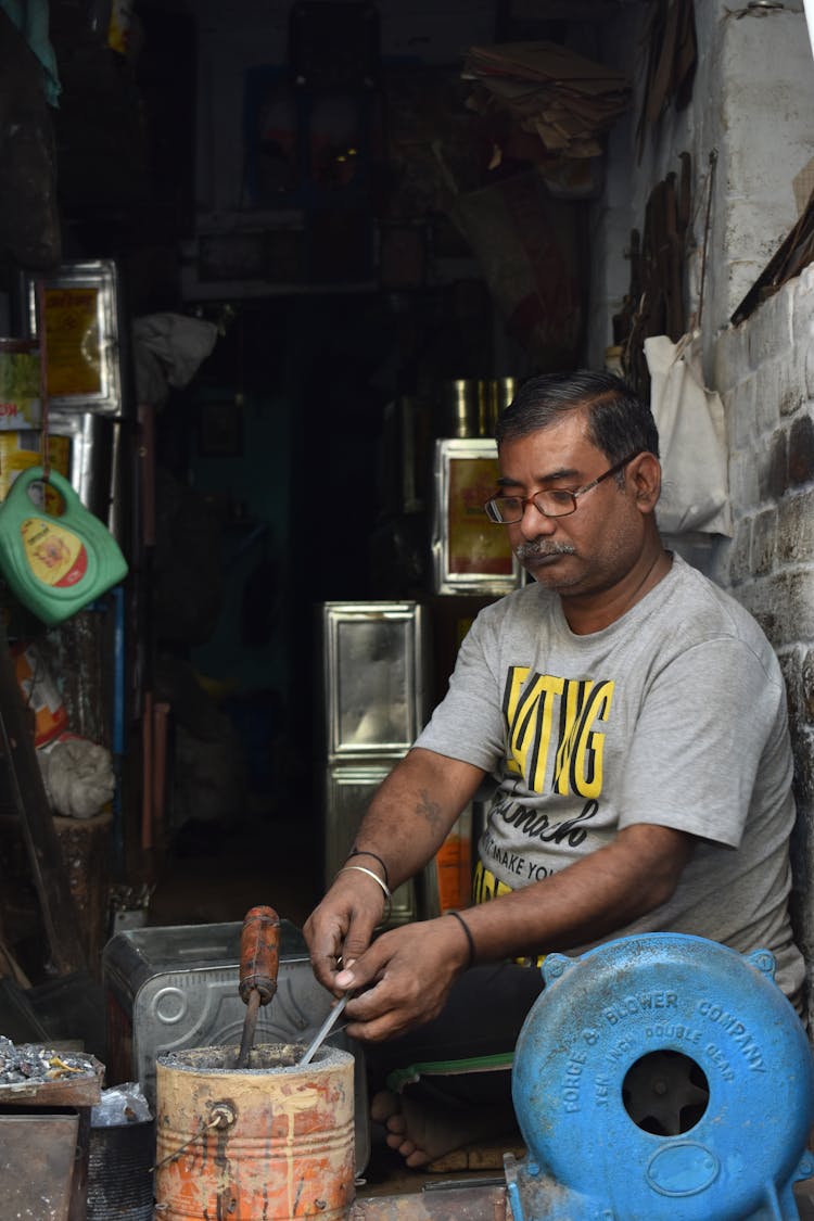 A Shopkeeper Heating A Metal Rod