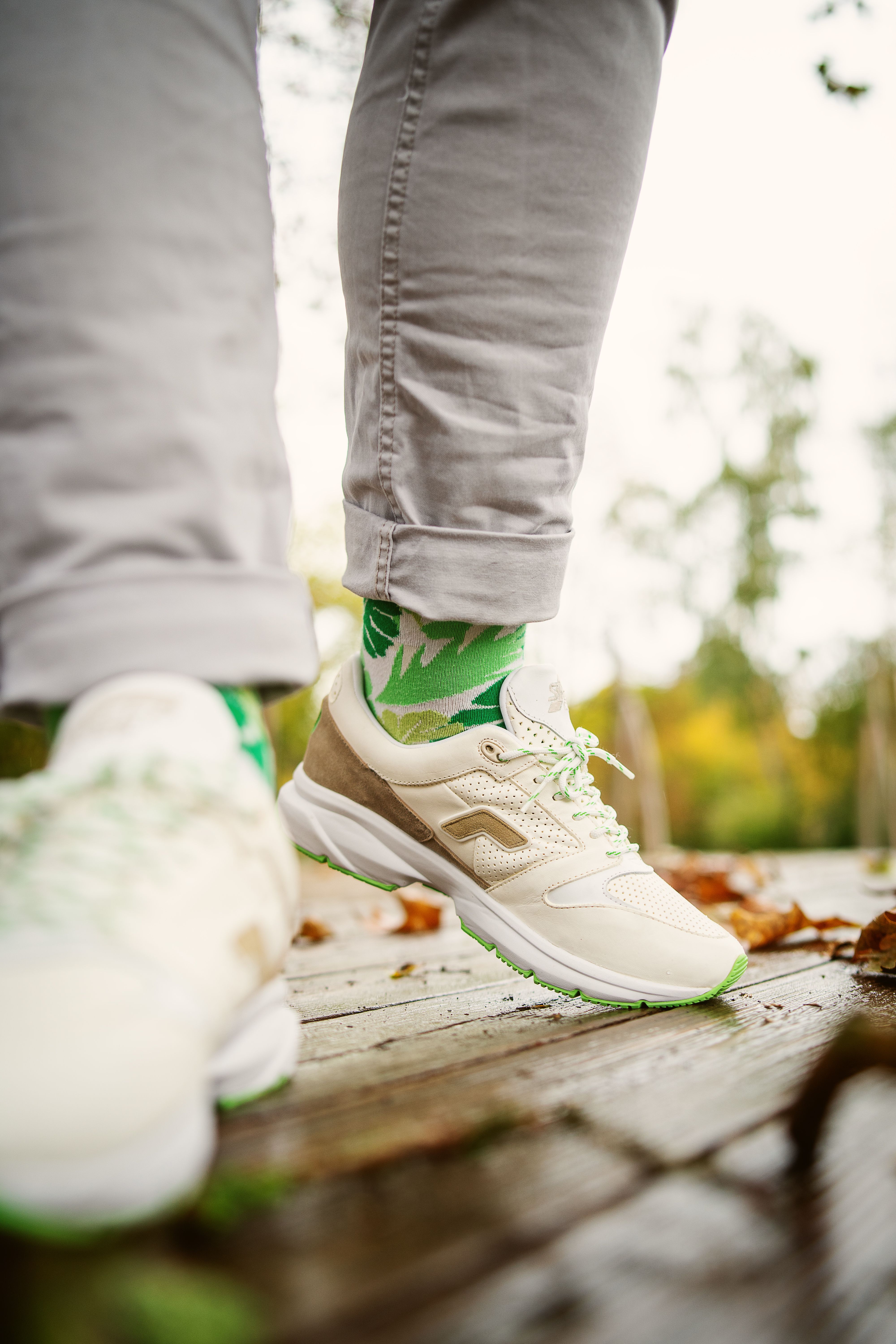 Fashionable sneakers and vibrant socks showcased on a rustic wooden path outdoors.