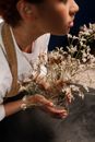 Woman Holding a Glass Vase with Dried Baby's-breath Flowers