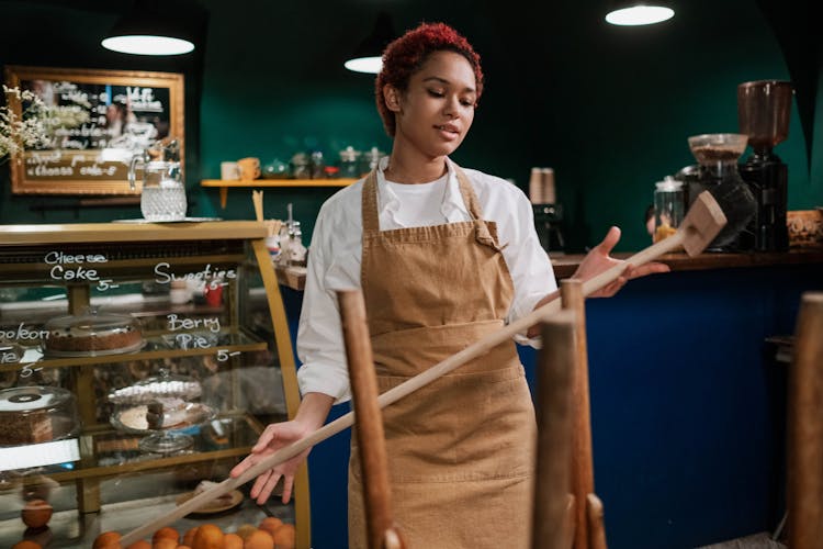 Woman Wearing An Apron Holding A Wood Broom