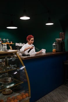 Barista tidying up the countertop in a cozy, dimly lit coffee shop.