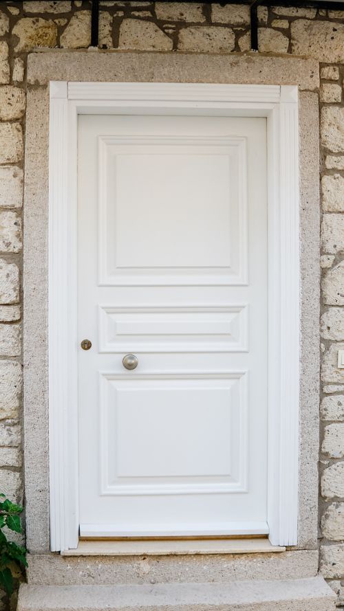 Free Elegant white wooden door set in a stone wall exterior in Alaçatı, Türkiye. Stock Photo