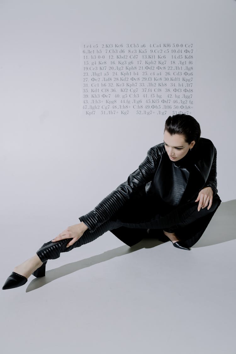 A Model In Leather Outfit Stretching Legs