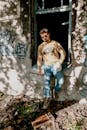 Man in Brown Tank Top and Blue Denim Jeans Standing Beside Wall