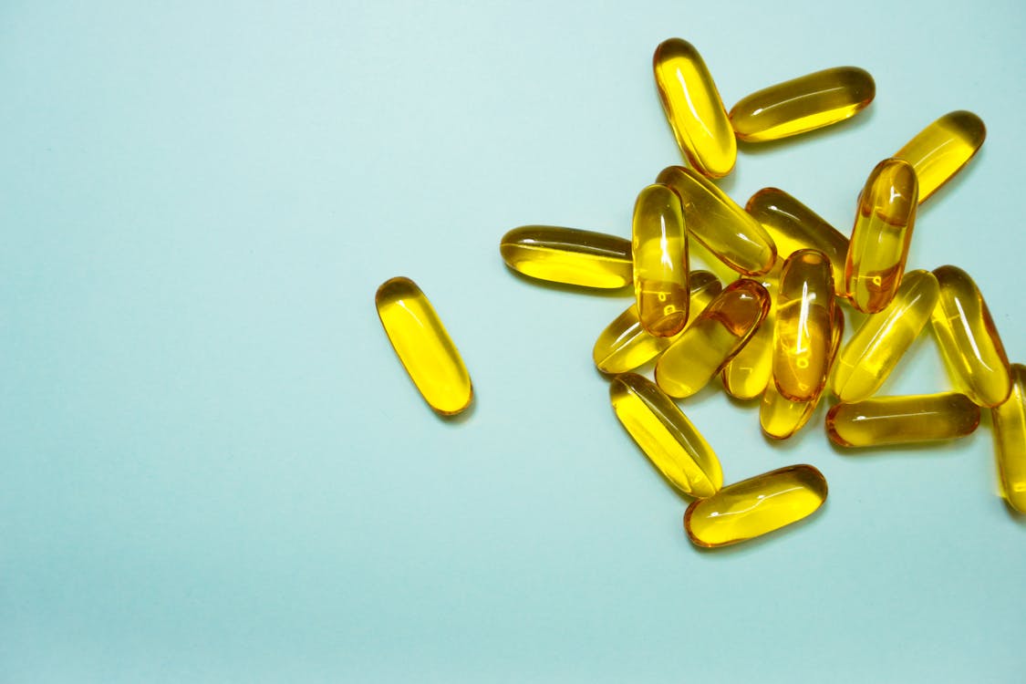 Free Yellow Capsules on Blue Surface Stock Photo
