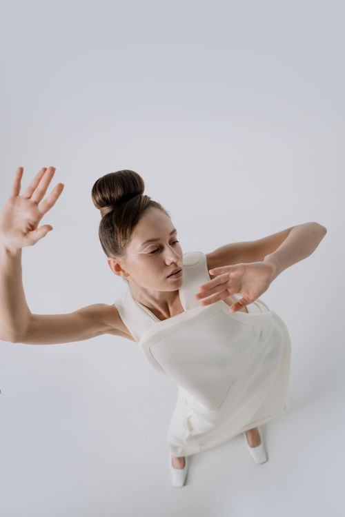 Free Elegant artistic portrait of a woman in a white dress, posed against a minimalist backdrop. Stock Photo