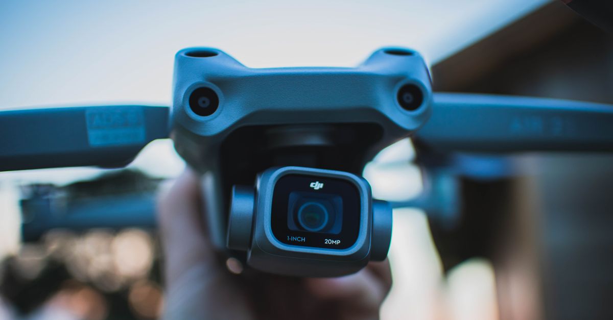 Detailed close-up of a hand holding a drone camera with blurry background, captured outdoors.