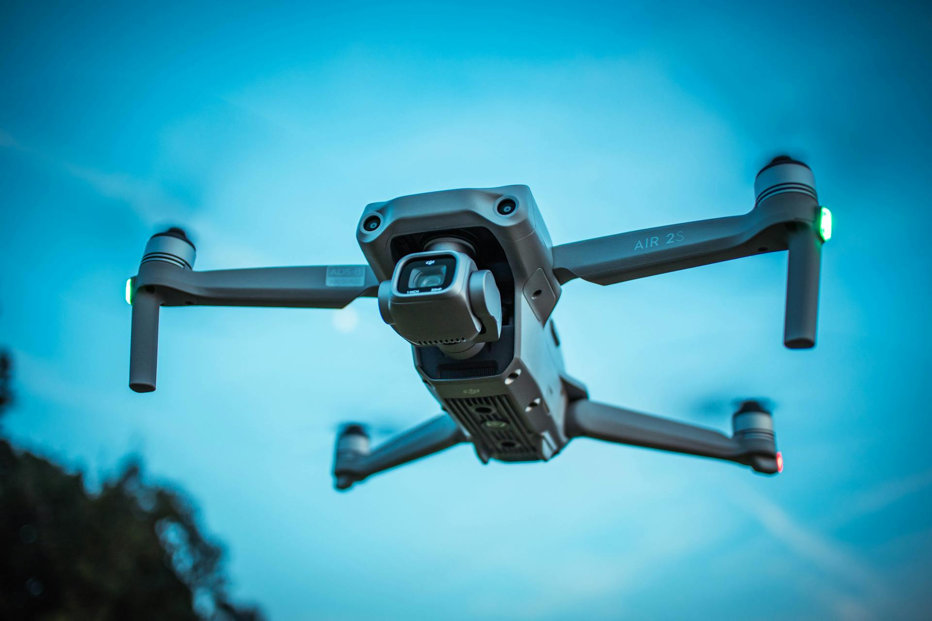 A modern drone soaring through a bright blue sky, showcasing advanced technology and aerial capabilities.