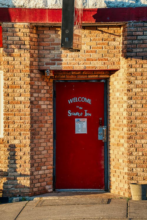 Red Door of an Inn with a Welcome Sign 