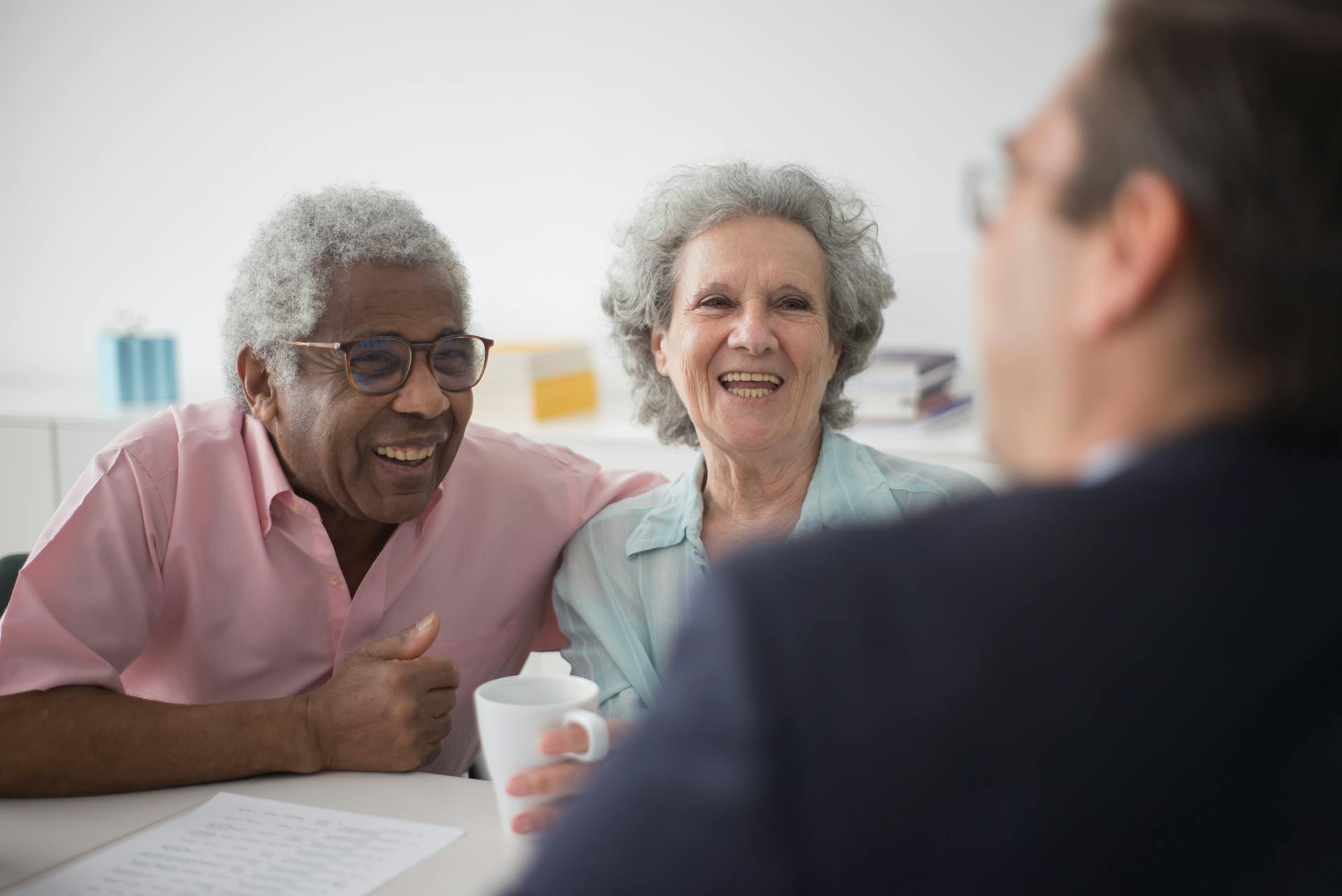 Happy elderly couple enjoying a conversation with a professional advisor indoors.