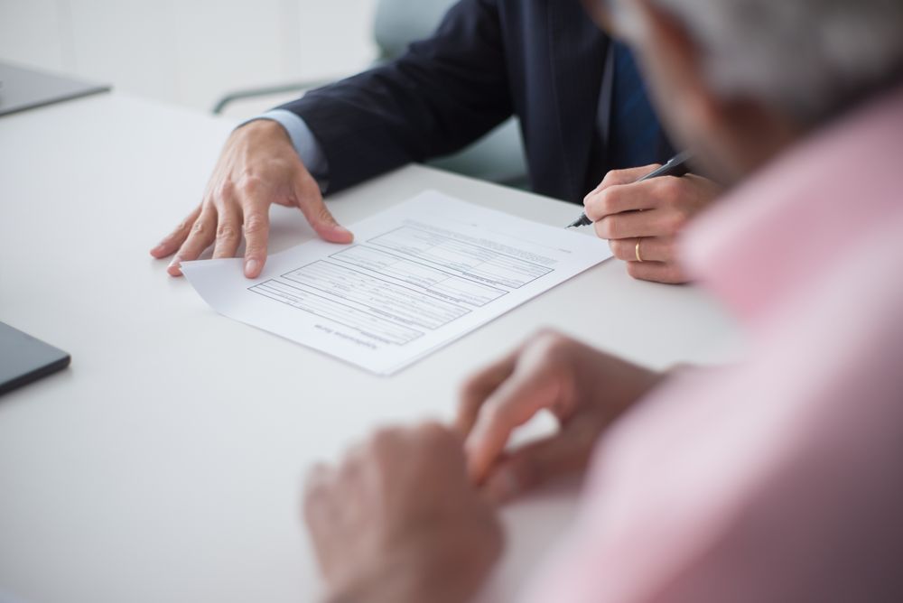 Two people at a table reviewing and signing a claim form — photo by Kampus Production on Pexels
