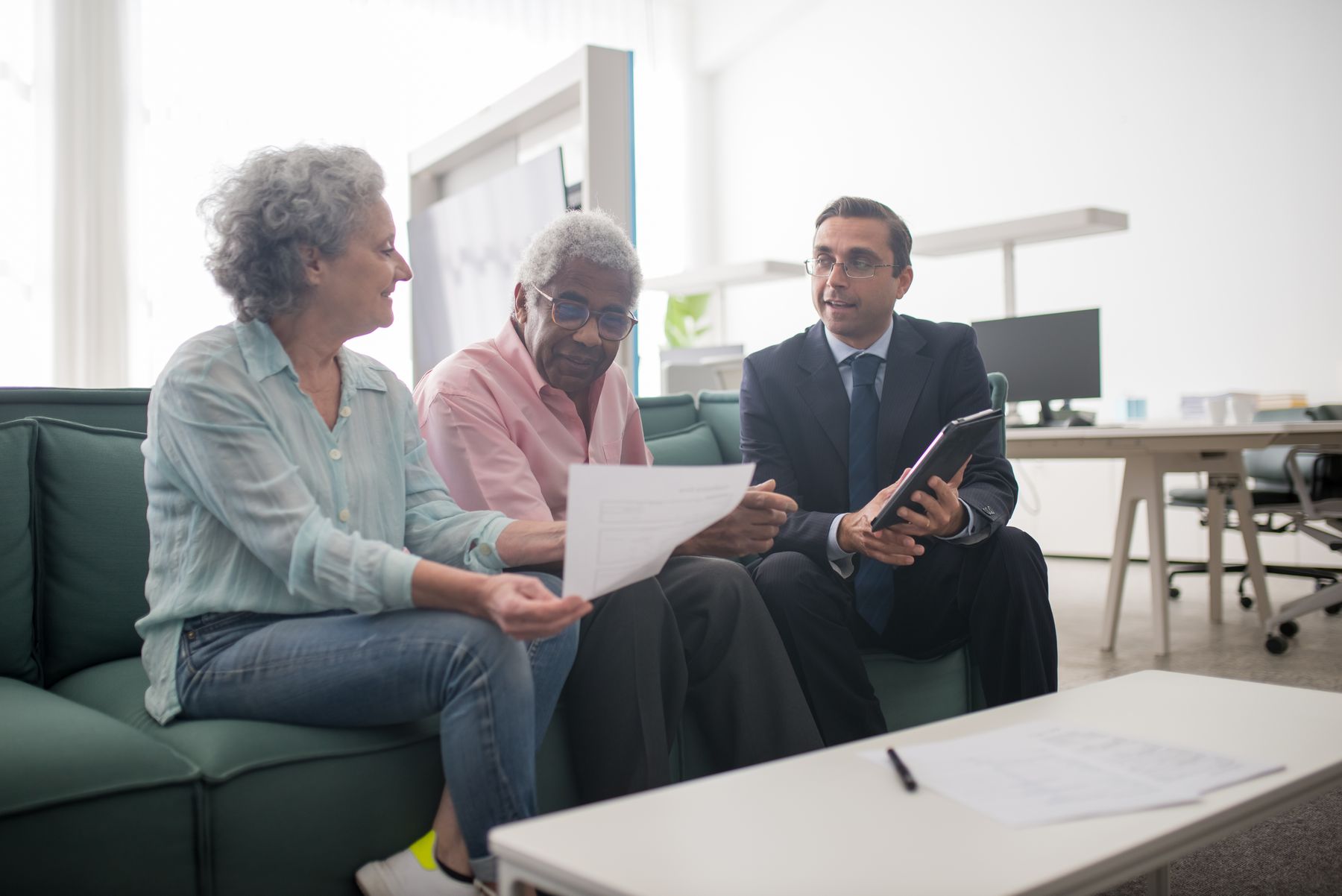 Two older adults reviewing documents with another person in an office