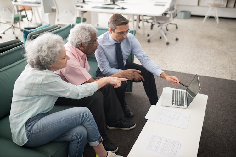 People Sitting On A Couch While Looking At The Screen Of Laptop