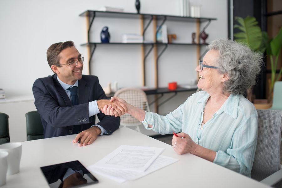 An elderly woman reviewing a policy with an advisor