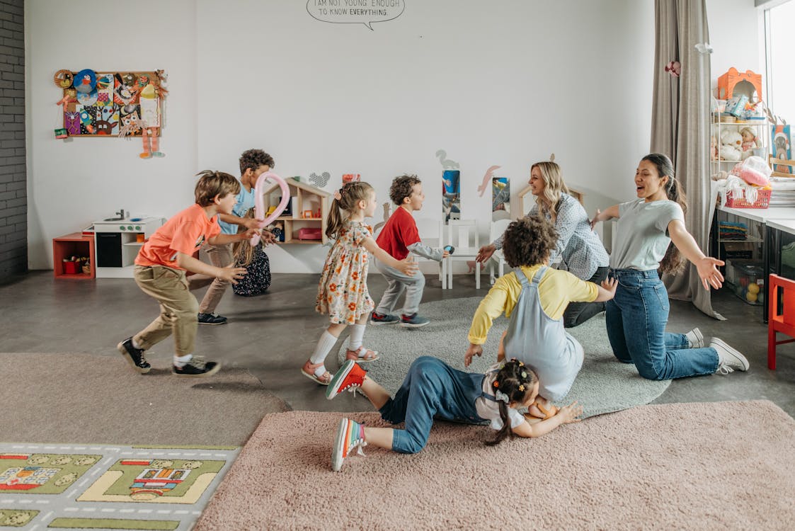 Free Women Kneeling on the Floor with Children in a Room Stock Photo
