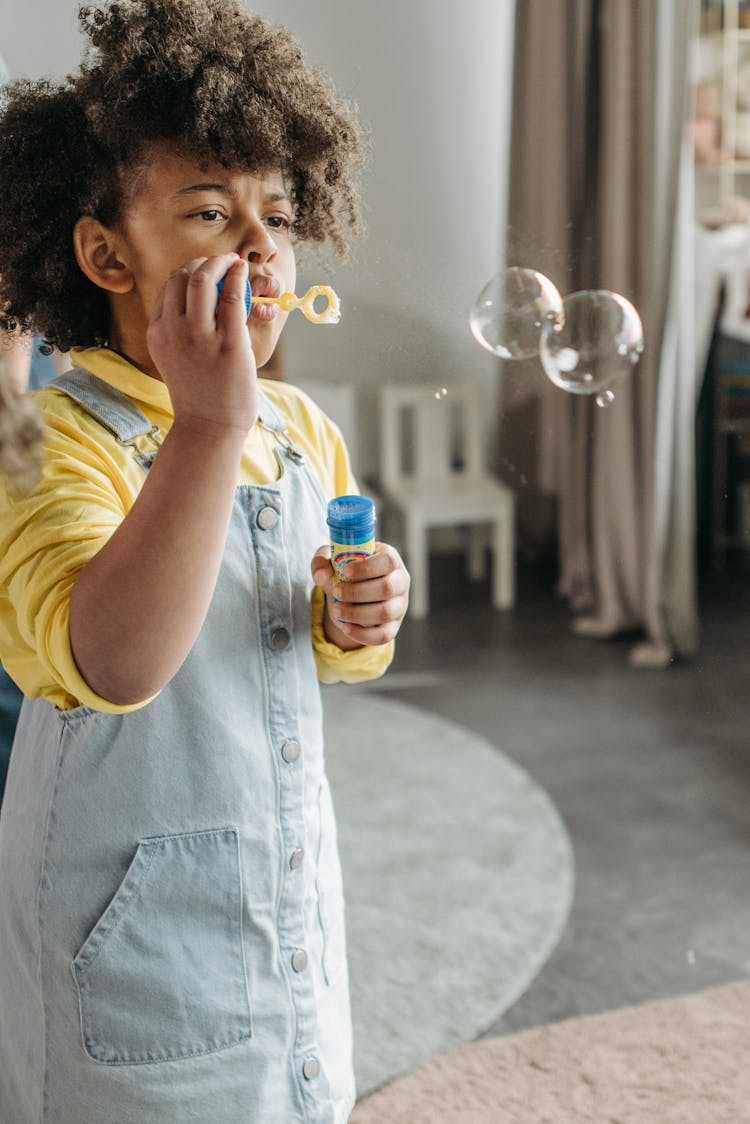 A Kid With Afro Hair Blowing Soap Bubbles