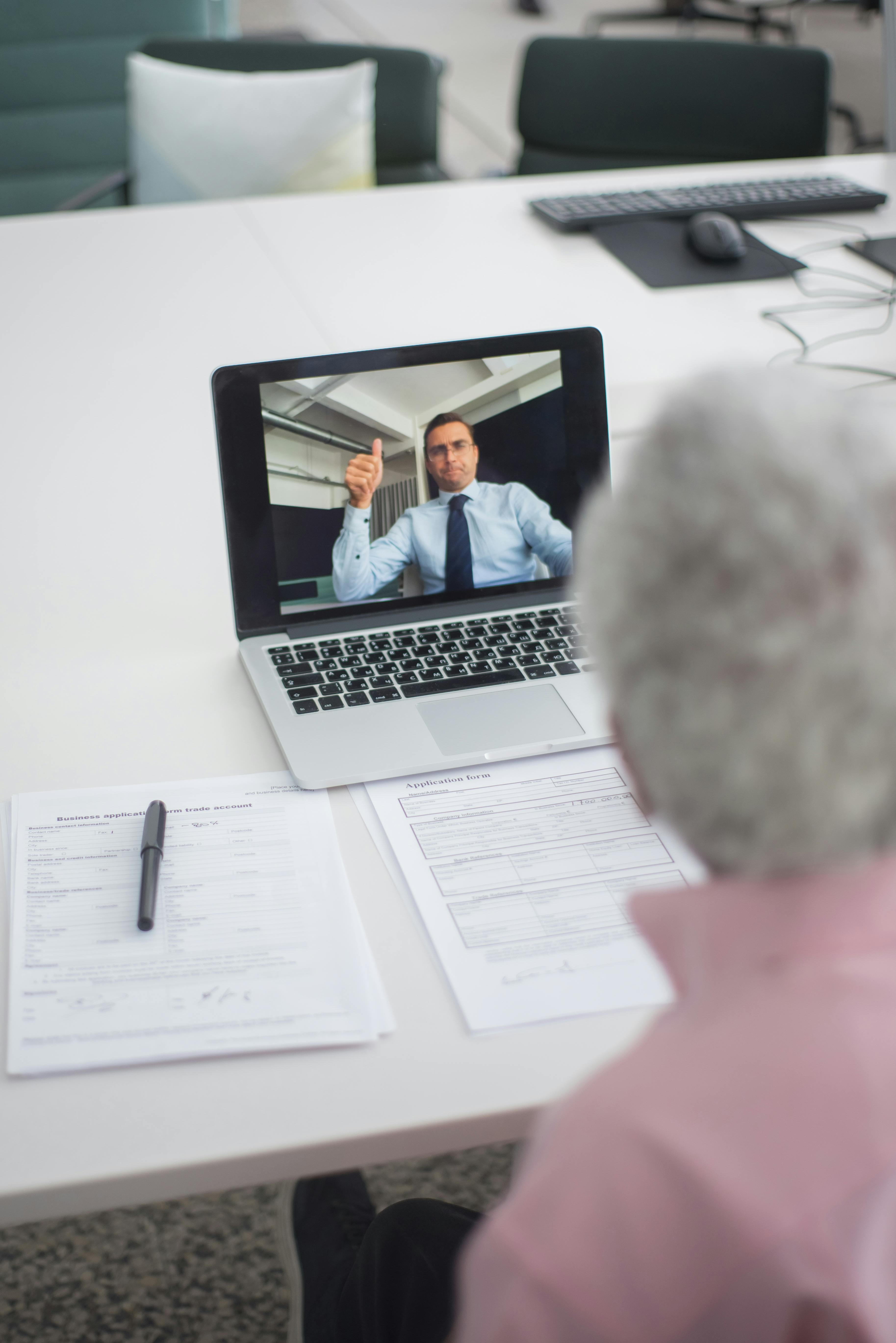 an elderly man on video call with an agent doing a hand sign