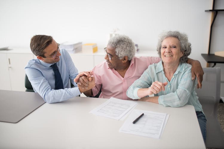 Insurance Agent Sitting Next To Smiling Clients