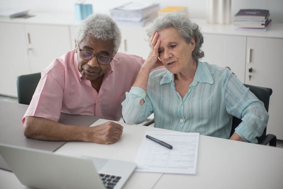 Older couple reviewing financial documents on a laptop