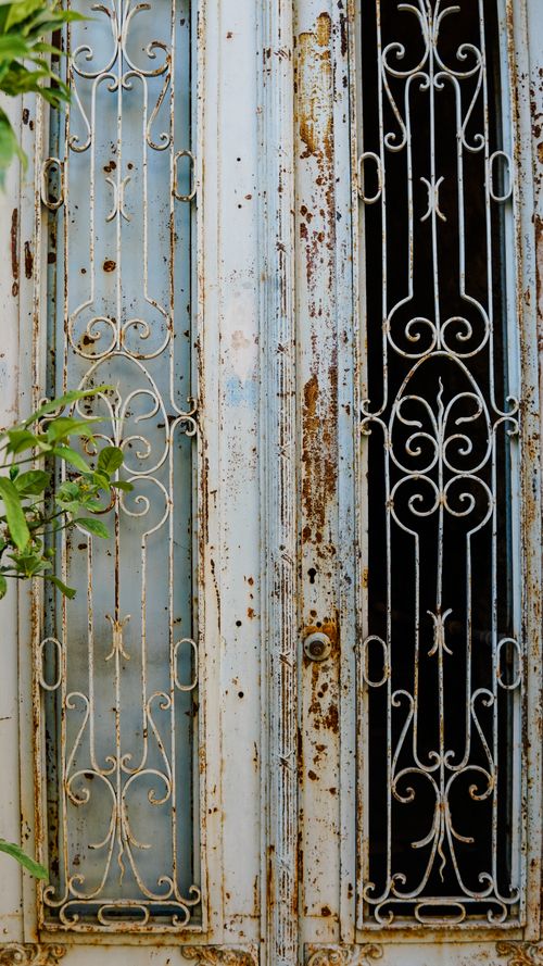 Free Rustic metal grilles adorn a vintage door in Alaçatı, showcasing intricate designs and a timeworn look. Stock Photo