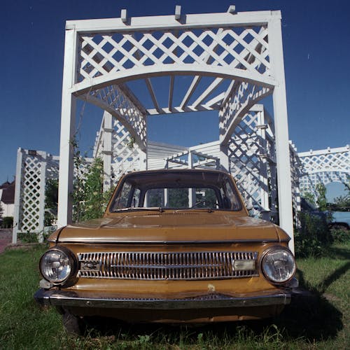 Free Brown Vintage Car Parked under Wooden Trellis Stock Photo