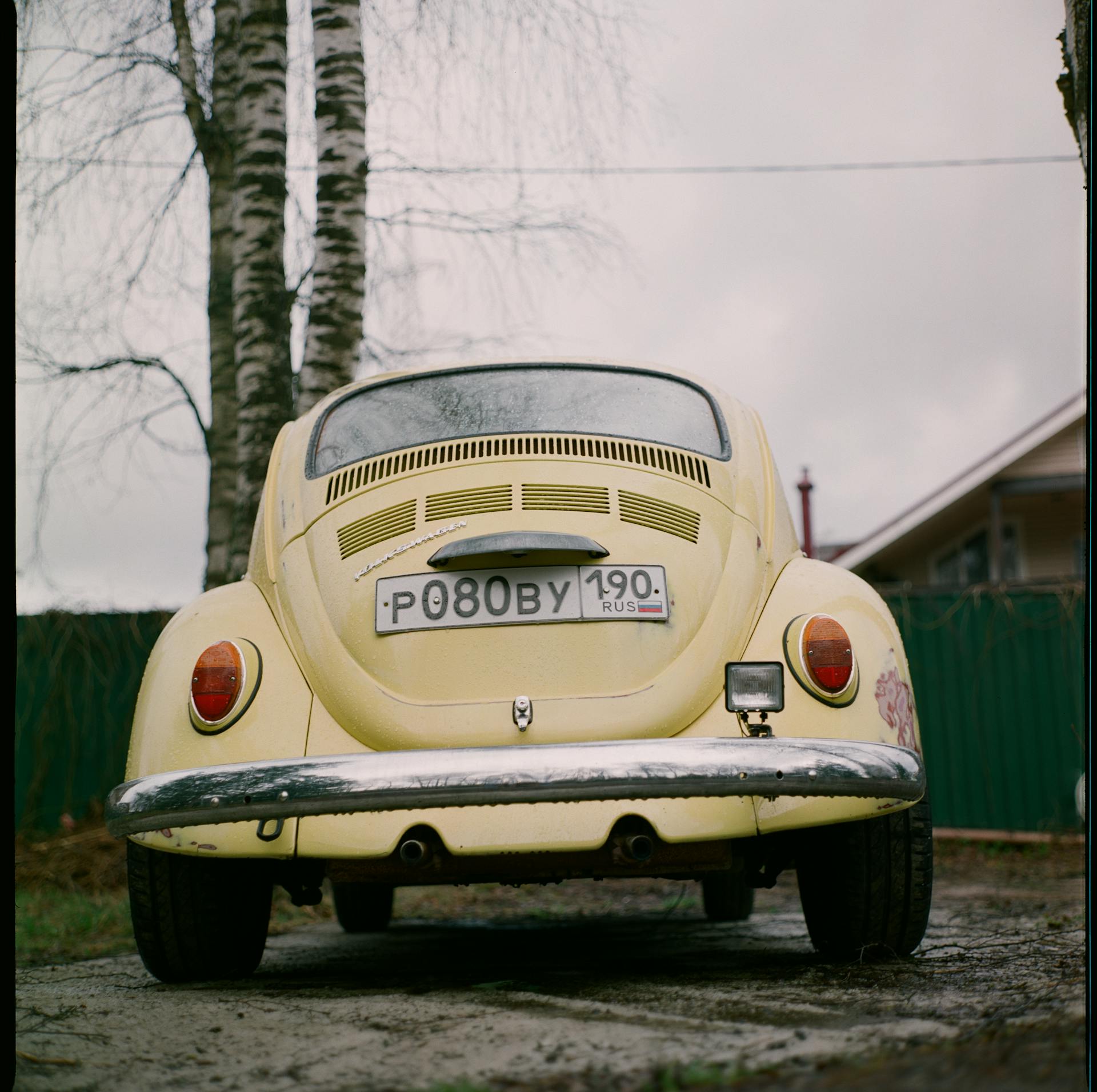 Rear view of a classic yellow Beetle parked outdoors, showcasing vintage charm.